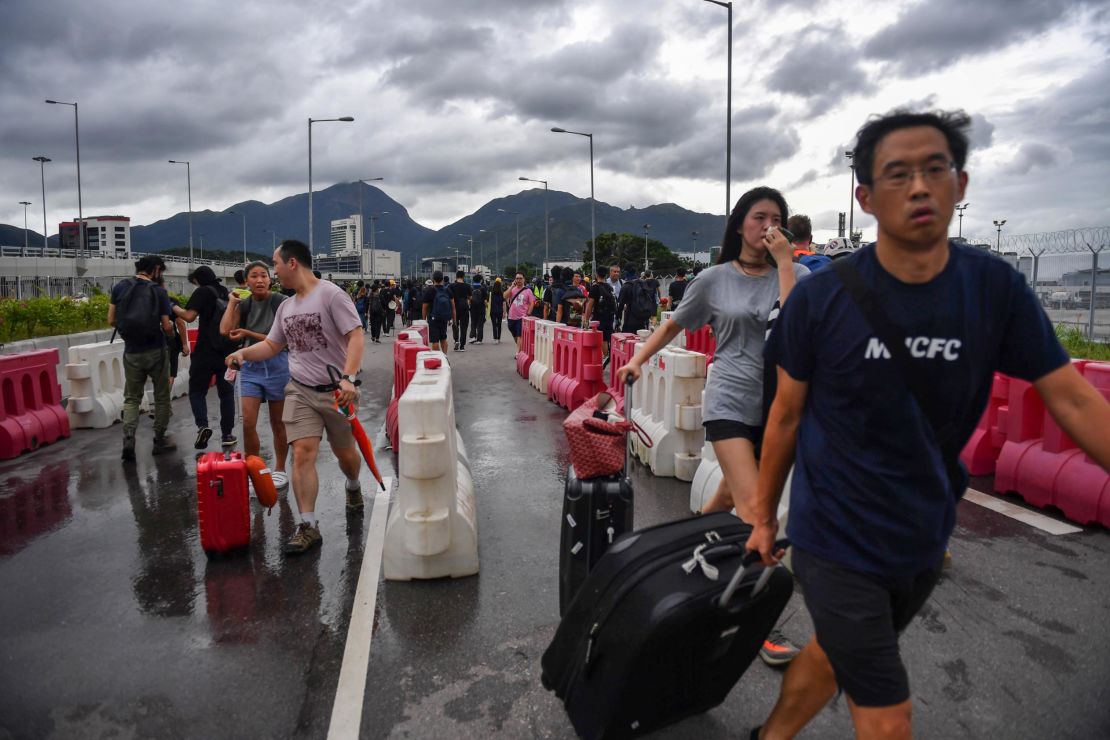 Passengers walk through barriers set up by protesters on a road near Hong Kong International Airport on September 1, 2019.