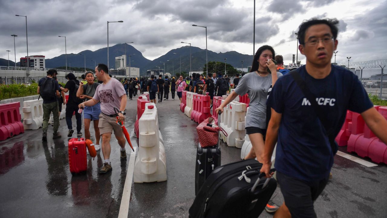 Passengers walk through barriers set up by protesters on a road near Hong Kong International Airport on September 1, 2019.