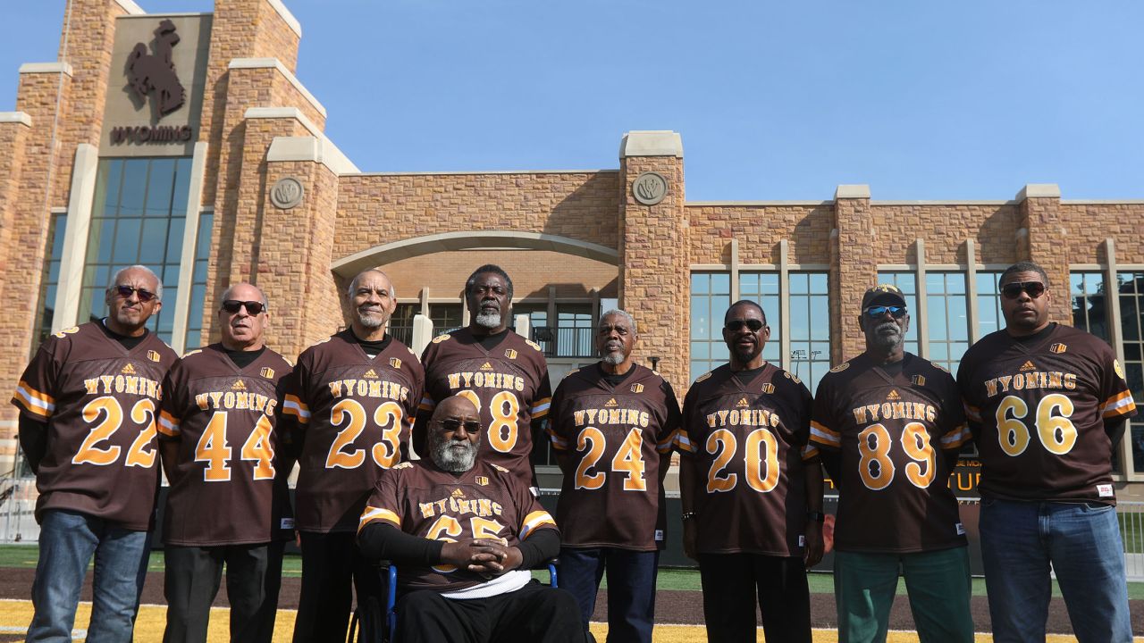 Members of the Black 14 pose for the camera at the University of Wyoming. From left: John Griffin, Tony Gibson, Lionel Grimes, Tony McGee, Ted Williams, Guillermo Hysaw, Roy Hill and Brian Lee, representing his father, Earl Lee. In front is Mel Hamilton.