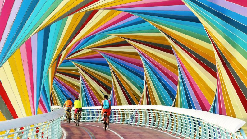 <strong>Qingdao, China: </strong>Cyclists pass through a gaily colored footbridge in east China's Shandong province. 