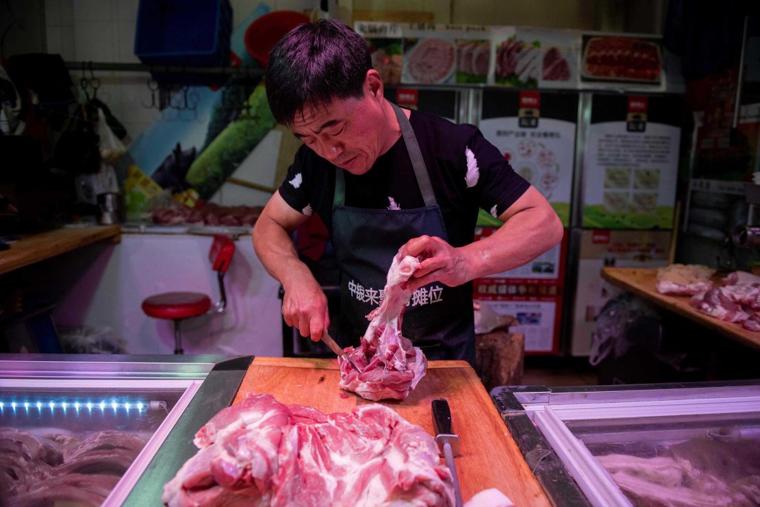 In this picture taken on July 10, 2019, a butcher cuts a piece of pork meat at his stall at a market in Beijing.