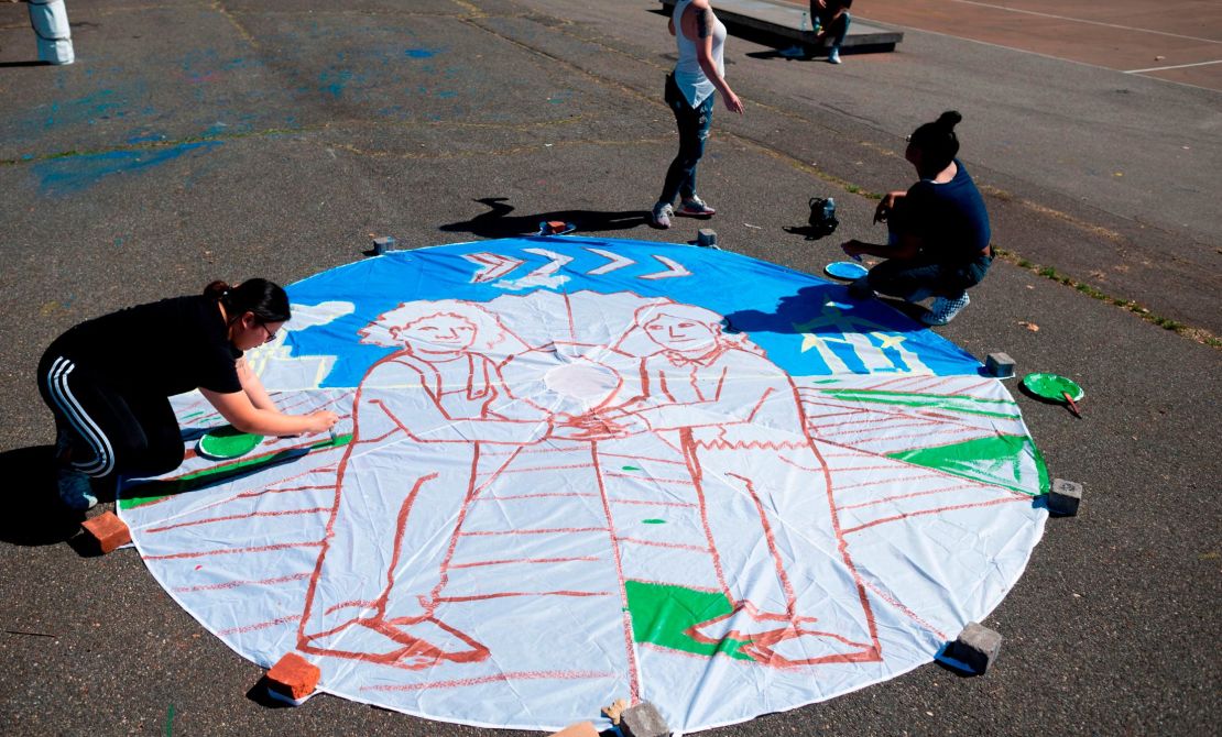 Children paint on a parachute made out of paper in New York City ahead of the September 20th Youth Climate Strike.