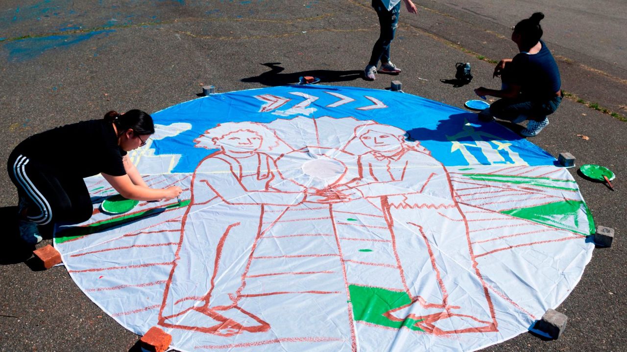 Children paint on a parachute made out of paper in New York City ahead of the September 20th Youth Climate Strike.