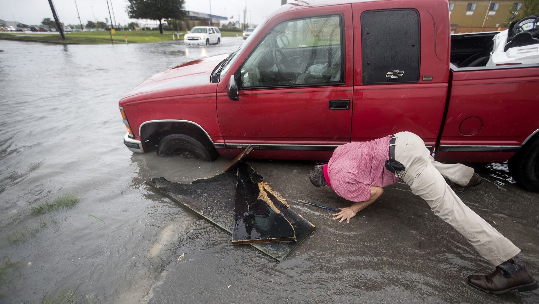 Felipe Morales works Tuesday on getting his truck out of a ditch filled with high water in Houston.