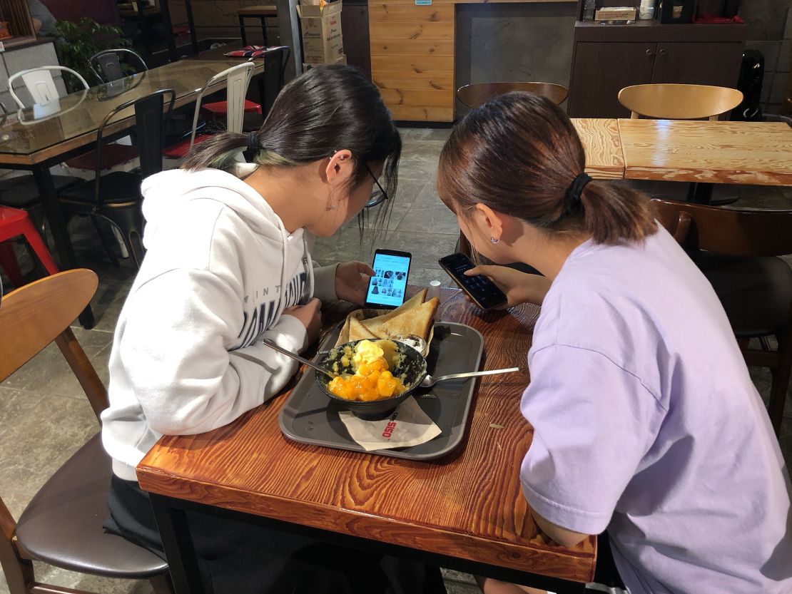 Yoo Chae-rin (left) shows photos of various hairstyles to her friend Kim Hyo-min  (right) in a coffee shop near Seoul in September 2019.