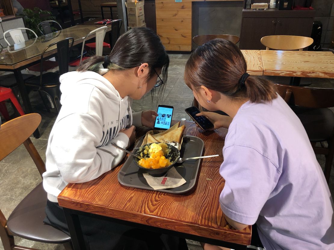 Yoo Chae-rin (left) shows photos of various hairstyles to her friend Kim Hyo-min (right) in a coffee shop near Seoul in September 2019.