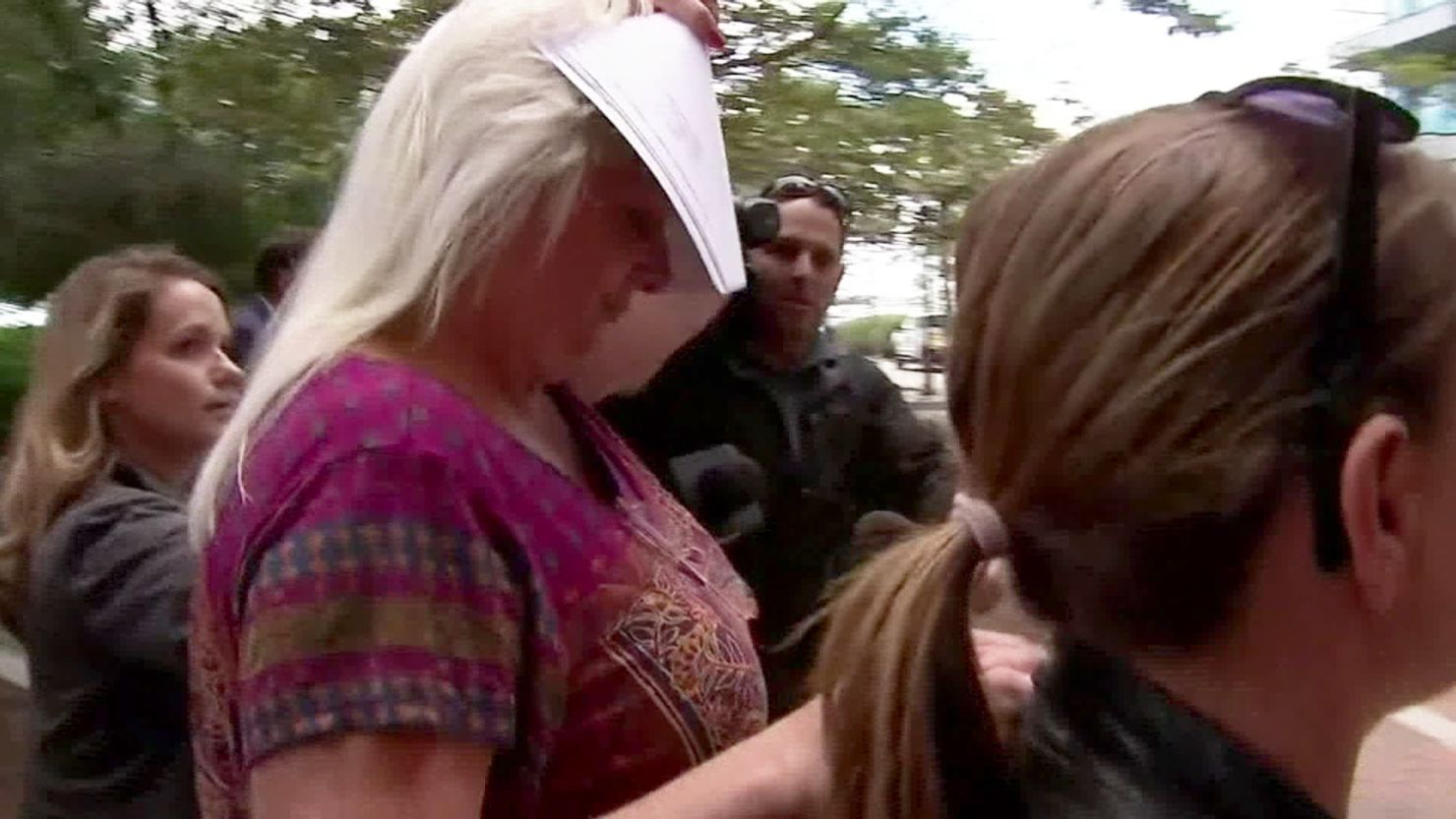 Kathleen Noftle covers her face as she walks into federal court in Boston