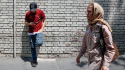 An Iranian man uses his mobile telephone as a woman walks by in the capital Tehran on July 8, 2019. - Iran's uranium enrichment levels passed 4.5 percent on today, exceeding the 2015 nuclear deal cap, Iran's atomic energy organisation spokesperson Behrouz Kamalvandi said according to the semi-official ISNA News Agency.