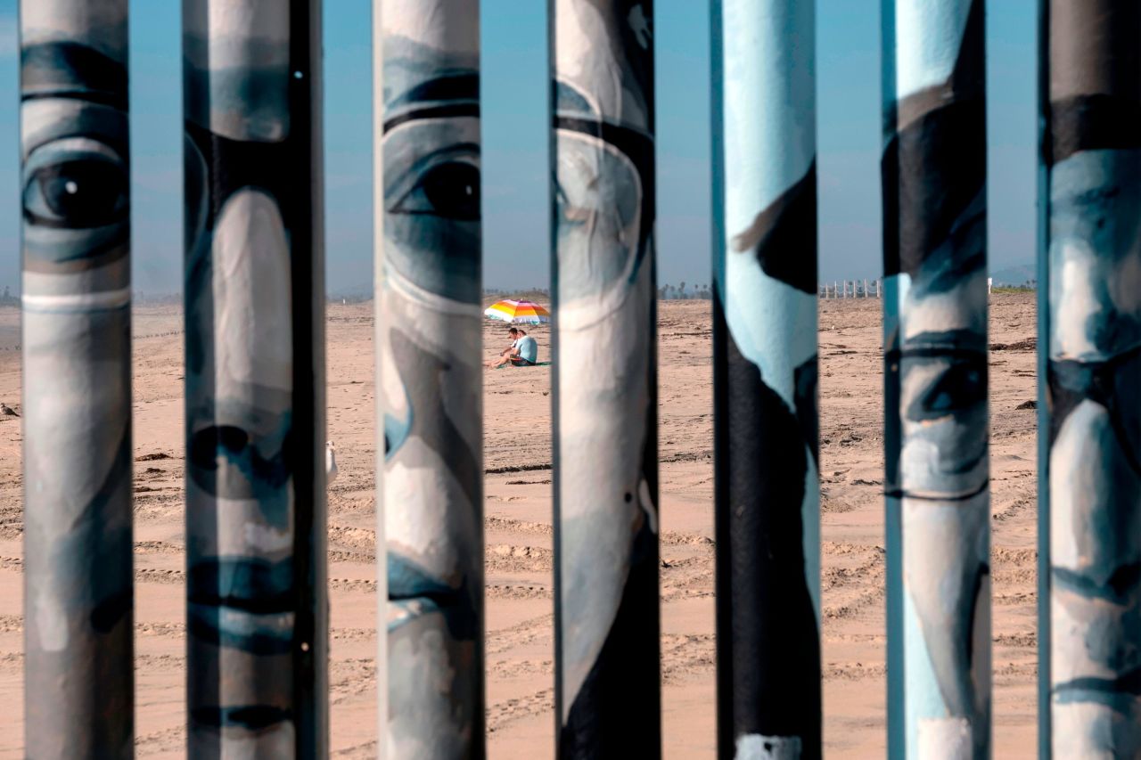 A couple sits on the beach as seen through the US-Mexico border fence from Playas de Tijuana, Baja California state, Mexico, on Saturday, September 14.