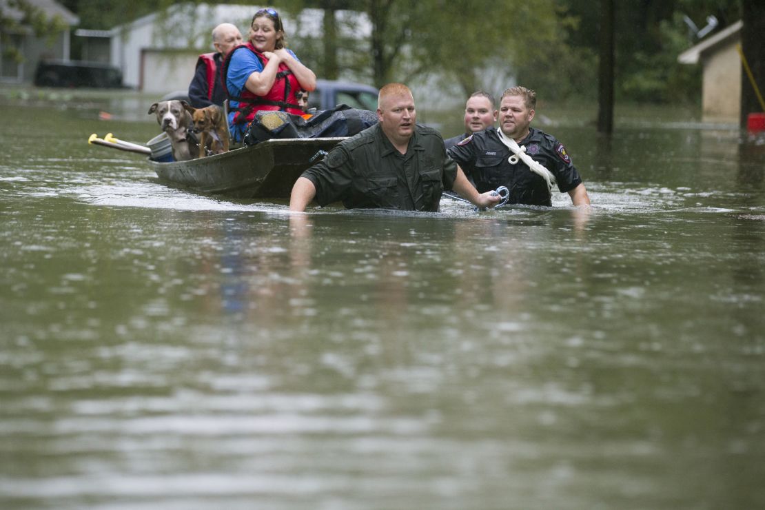 Police pull a boat carrying residents Thursday from their flooded neighborhood in Splendora, Texas.