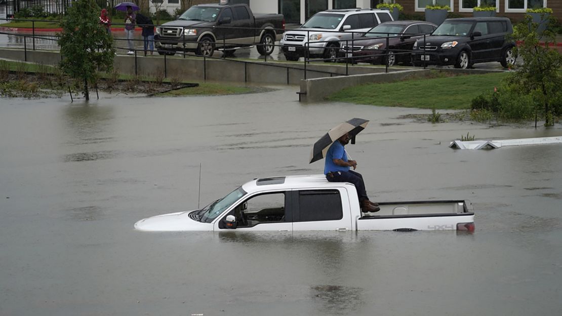 A man sits on top of a truck on a flooded road Thursday in Houston. Members of the Houston Fire Department gave him a life jacket and walked him to dry land.