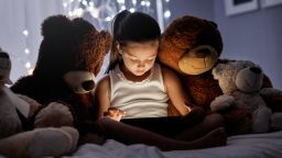 Shot of an adorable little girl using a digital tablet in bed at night