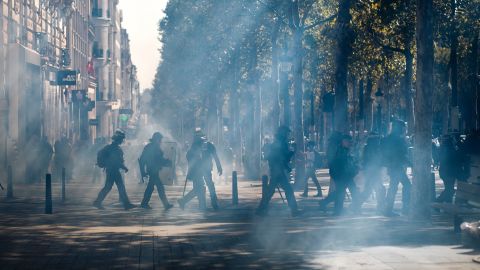 Police walk through a tear gas cloud on the Champs-Élysées Saturday.