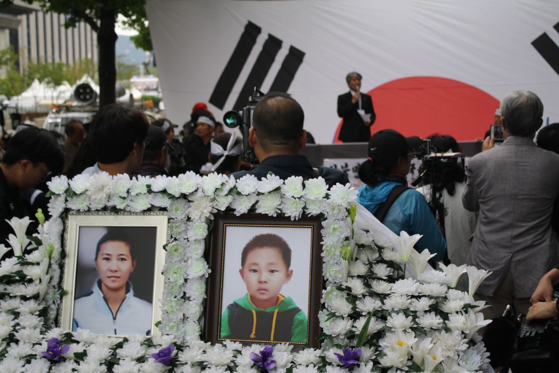 Photos of Han Sung-ok and Kim Dong-jin are displayed at a protest in Seoul after their deaths. 