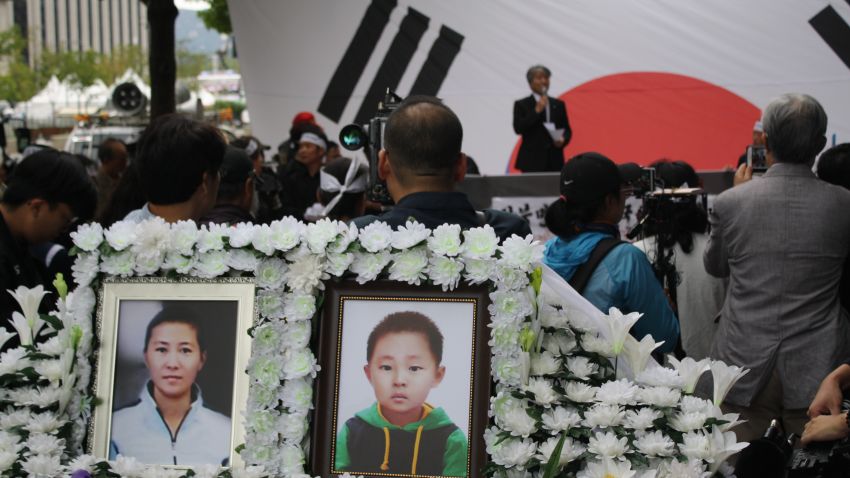 Photos of Han Sung-ok and Kim Dong-jin are displayed at a protest in Seoul after their deaths.