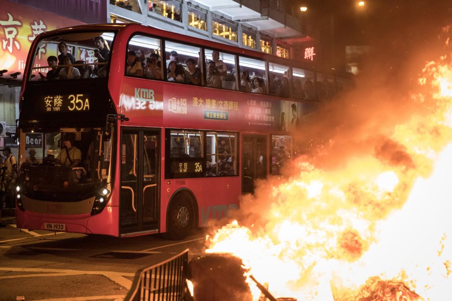 Bus passengers look at a burning barricade lit by pro-democracy protesters in front of the Mong Kok police station on Sunday, September 22.