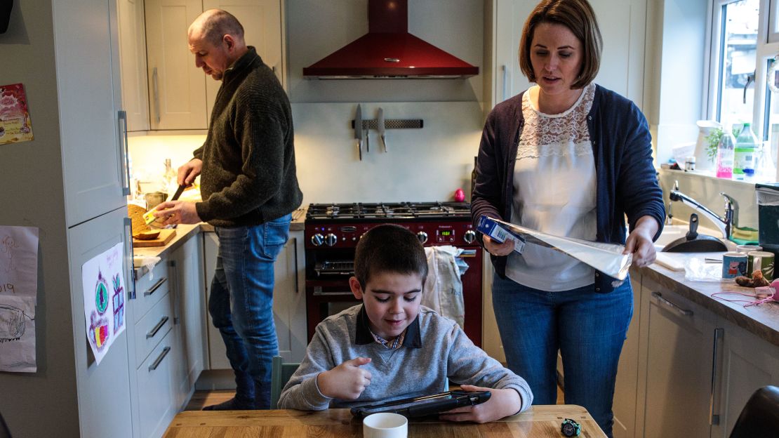 Alfie Dingley watches a video on a tablet as his parents Drew Dingley and Hannah Deacon prepare lunch at their home on January 13, 2019 in Kenilworth, England.  