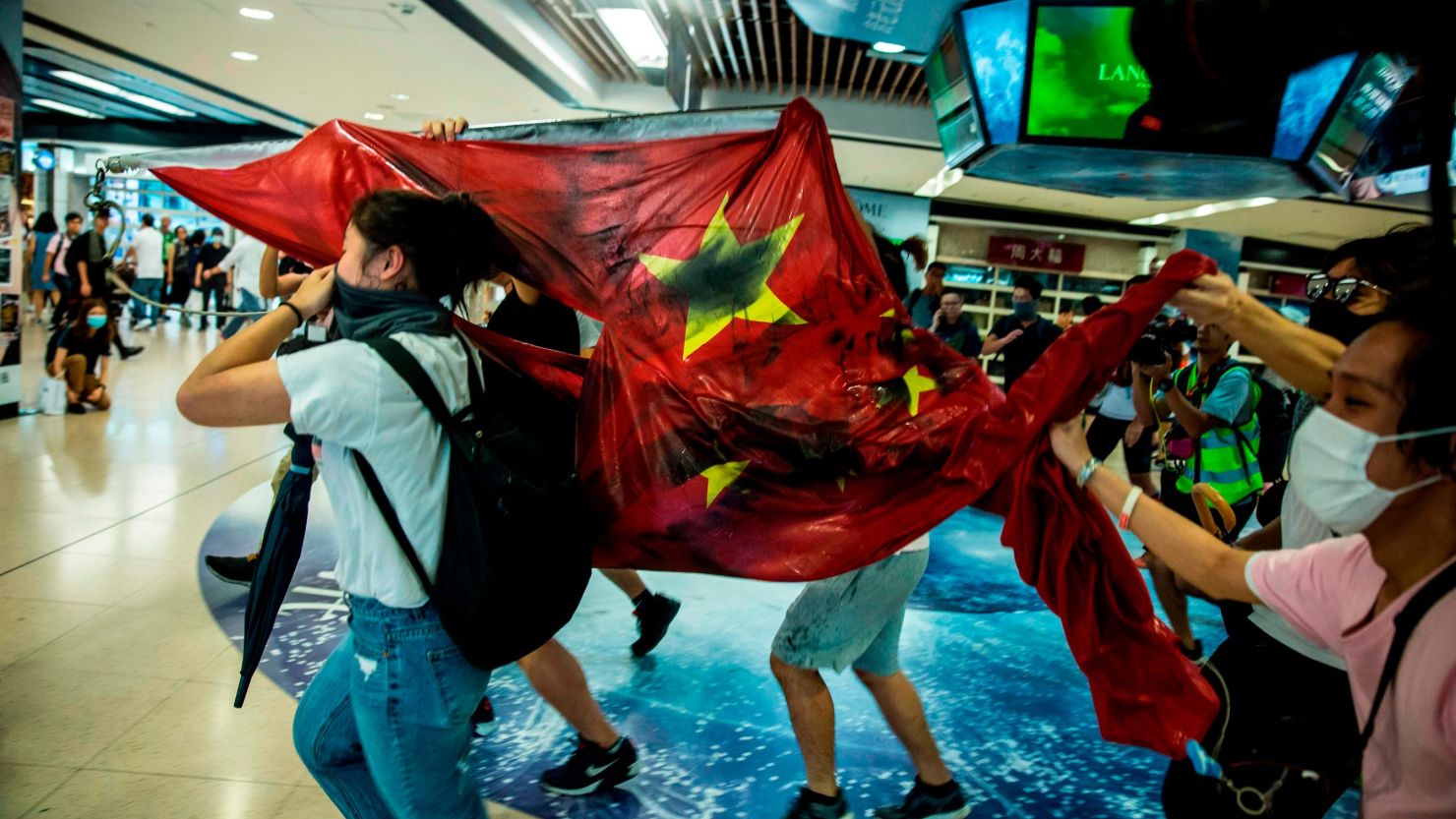 Pro-democracy protesters desecrate the Chinese national flag during a protest at the New Town Plaza shopping mall in Hong Kong's Sha Tin district on September 22, 2019.