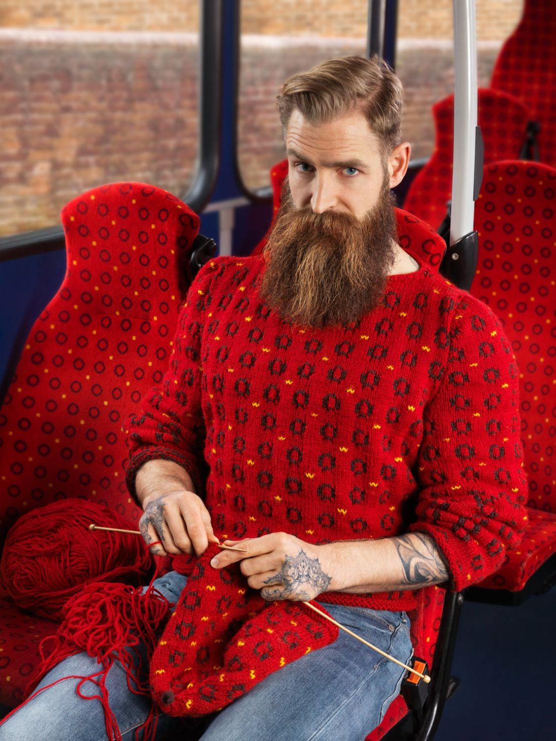 A model wears a red sweater to match bus seats.