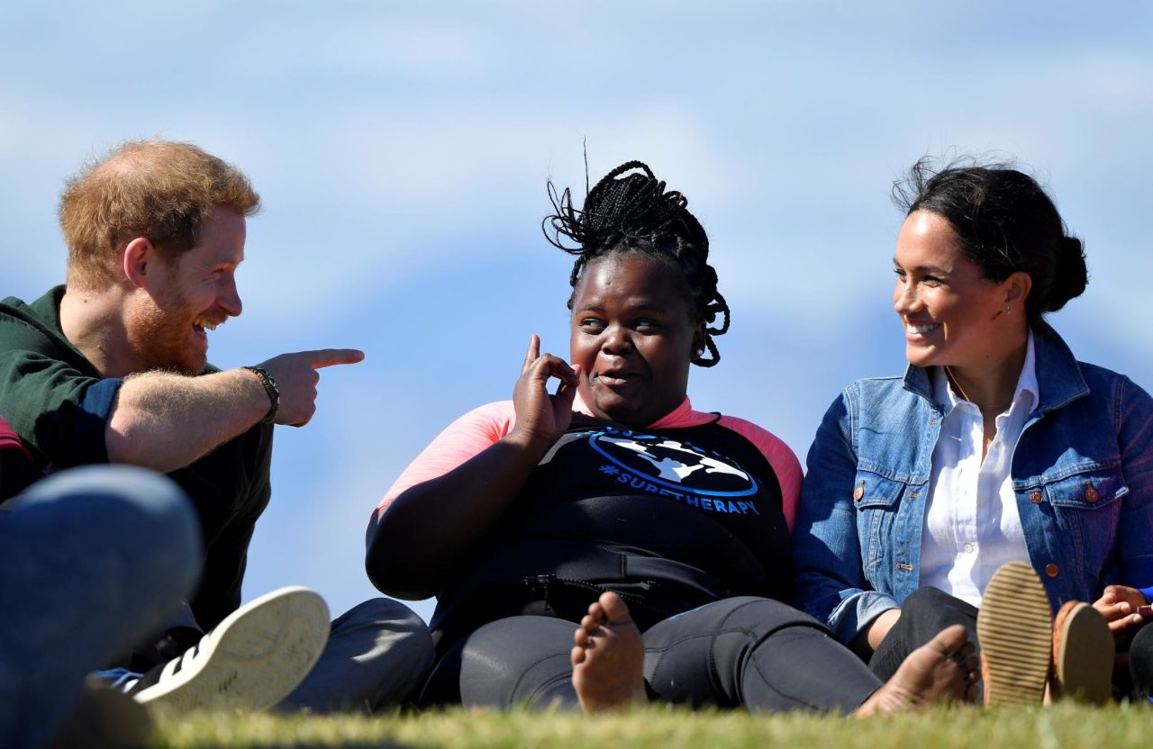 The Duke and Duchess of Sussex talk with a member of the of Waves for Change at Monwabisi Beach in Cape Town. Waves for Change is a charity that takes children out of violent neighborhoods and teaches them how to surf as a way to heal and escape.