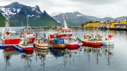 Fishing boats at the pier with mountain in the background at Husoy village, Senja island, Norway
