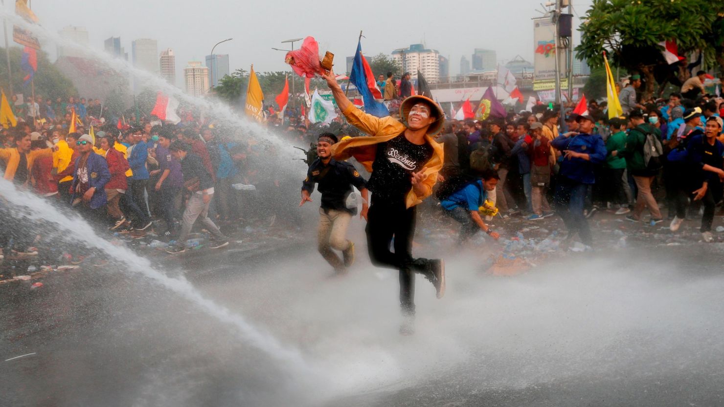 Student protesters hurl objects as they are sprayed by a police water cannon truck during a protest outside the parliament in Jakarta, Indonesia, on September 24, 2019. 