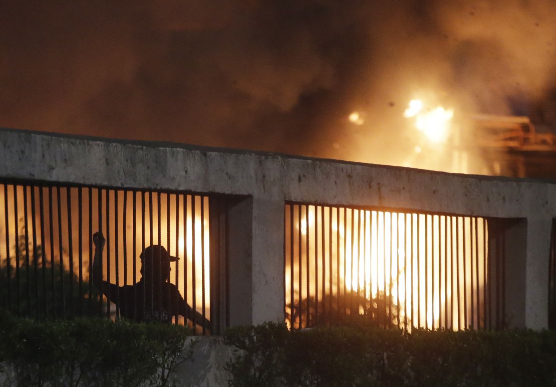 Student protesters throw stones at riot police as a gate burns in the background during a protest outside the parliament in Jakarta, Indonesia, on September 24, 2019. 