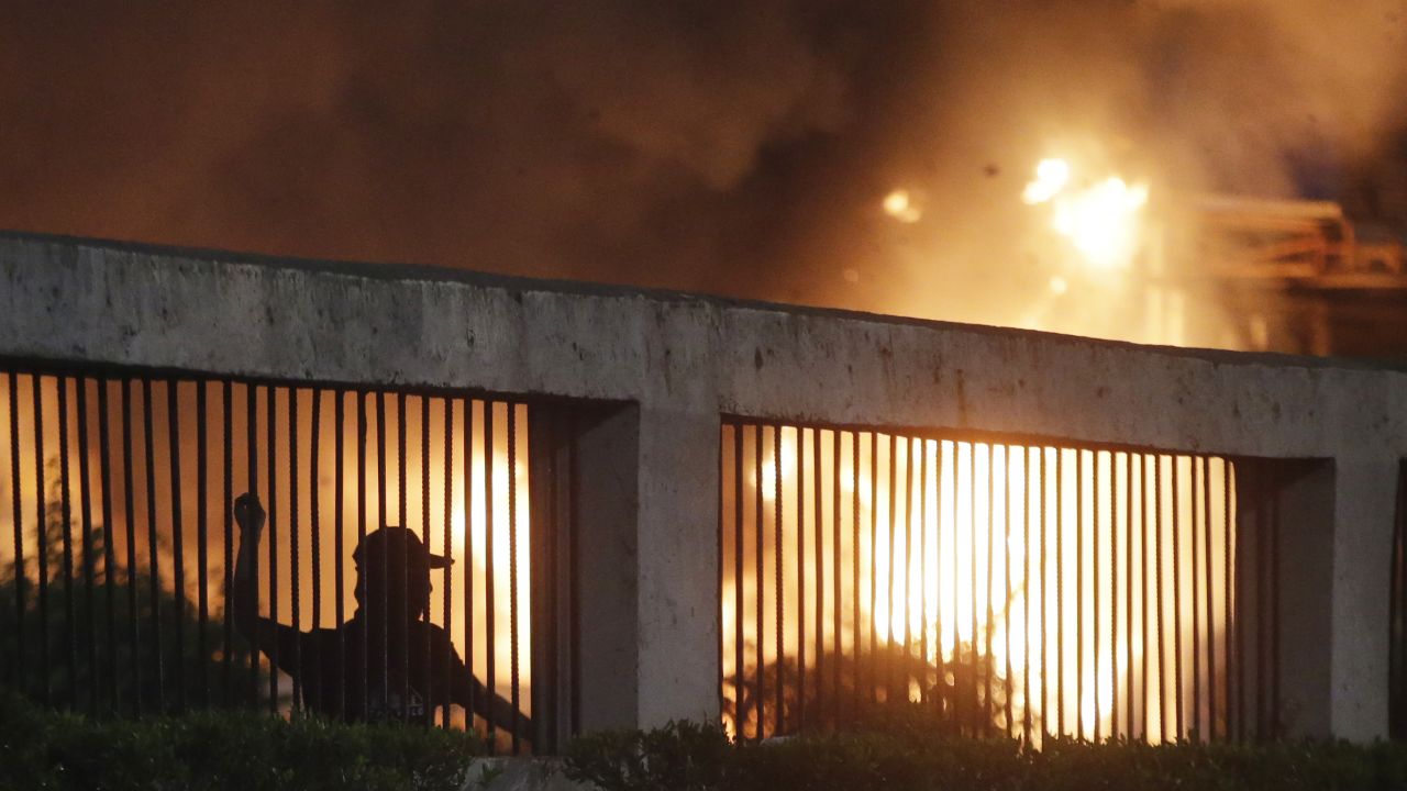 Student protesters throw stones at riot police as a gate burns in the background during a protest outside the parliament in Jakarta, Indonesia, on September 24, 2019.