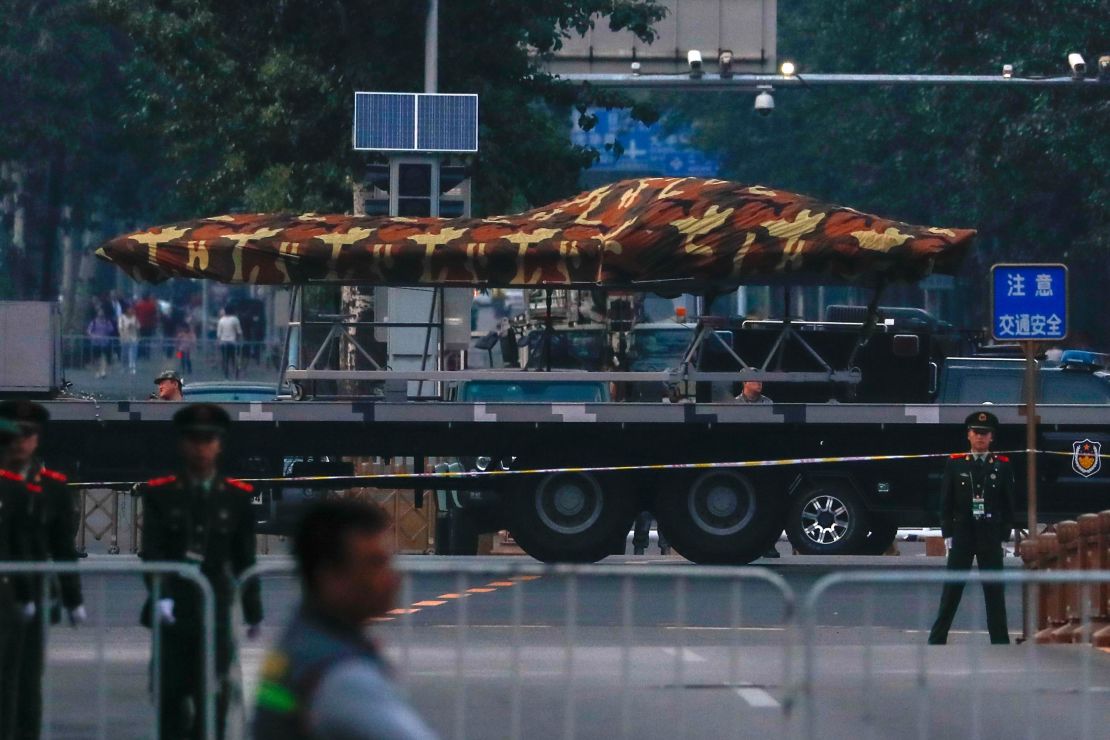 Chinese paramilitary policemen stand guard as a Chinese military vehicle possibly carrying a drone participates in an October 1 parade rehearsal.