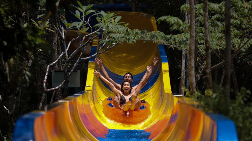 Theme park patrons slide down on a floater on the world's longest water slide at Escape theme park in Teluk Bahang, Malaysia on September 25, 2019. - One of the world's longest water slides was unveiled in Malaysia on September 25, a kilometre-long chute that starts from a hilltop before twisting and turning through dense jungle and splashing into a pool. (Photo by SADIQ ASYRAF / AFP)        (Photo credit should read SADIQ ASYRAF/AFP/Getty Images)
