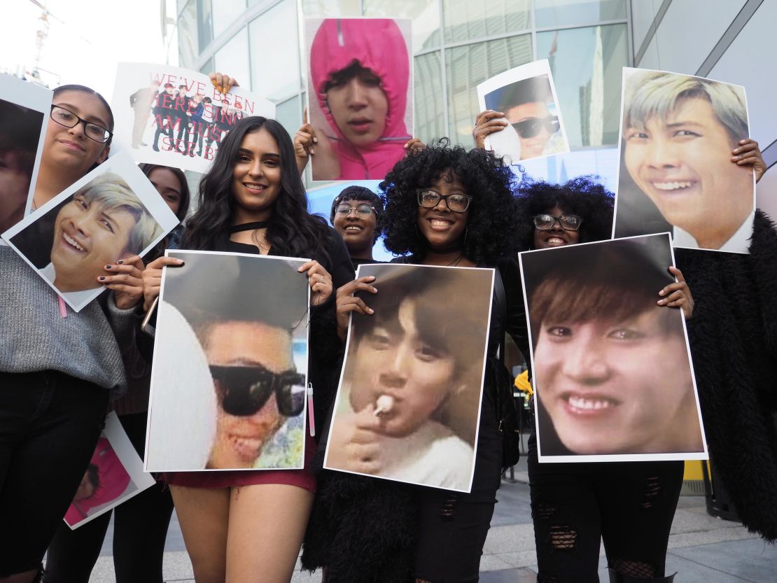 Fans of the Korean boy band group BTS pose with photos of their idols outside the 2017 American Music Awards, November 19, 2017 in Los Angeles, California.