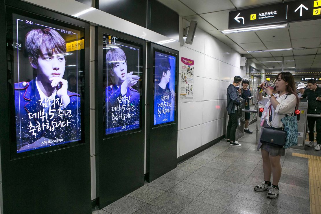A fan takes pictures of photos of BTS singer Jin which are displayed at Hongdae Subway Station on June 2, 2018 in Seoul, South Korea. Fans bought the advertising space to celebrate Jin's 5th anniversary of his debut with BTS.
