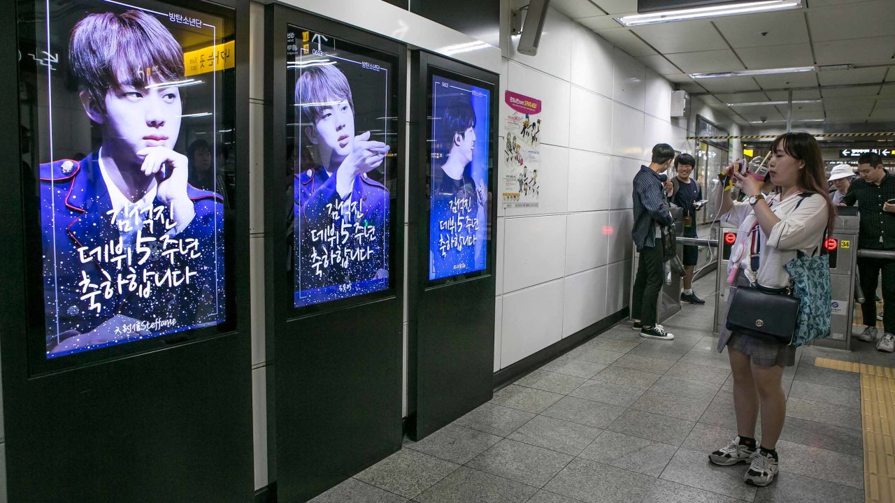 A fan takes pictures of photos of BTS singer Jin which are displayed at Hongdae Subway Station on June 2, 2018 in Seoul, South Korea. Fans bought the advertising space to celebrate Jin's 5th anniversary of his debut with BTS.