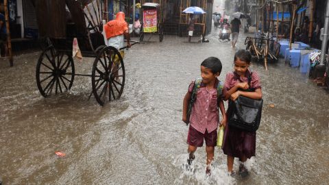 Indian schoolchildren walk through a flooded road during heavy rain in Kolkata on September 25, 2019.
