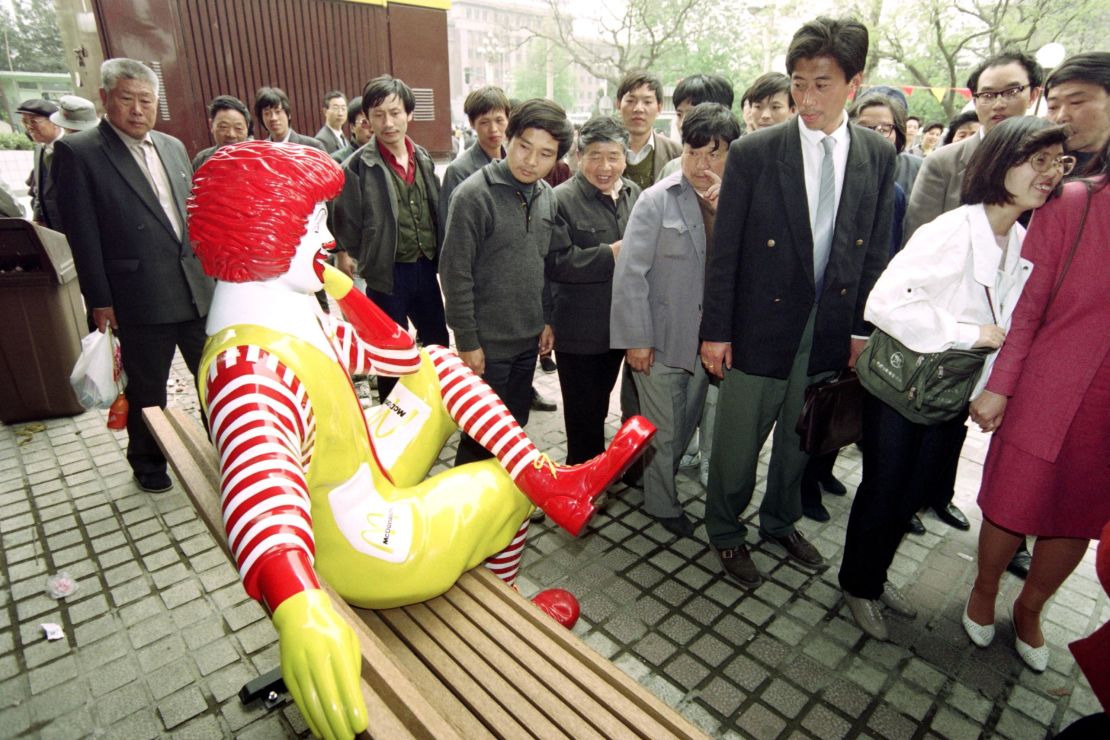 Passers-by keep their distance from Ronald McDonald as he sits outside the first McDonalds restaurant to be opened in Beijing on April 20, 1992.