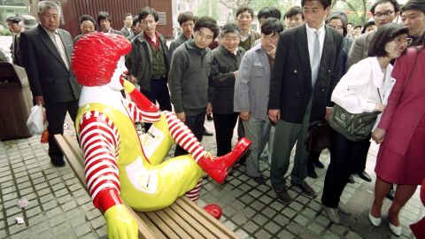 Passers-by keep their distance from Ronald McDonald as he sits outside the first McDonalds restaurant to be opened in Beijing on April 20, 1992.