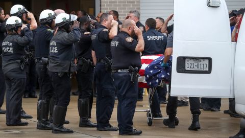 Law enforcement officers saulte as Dhaliwal's body is taken to a medical examiner's facility Friday.