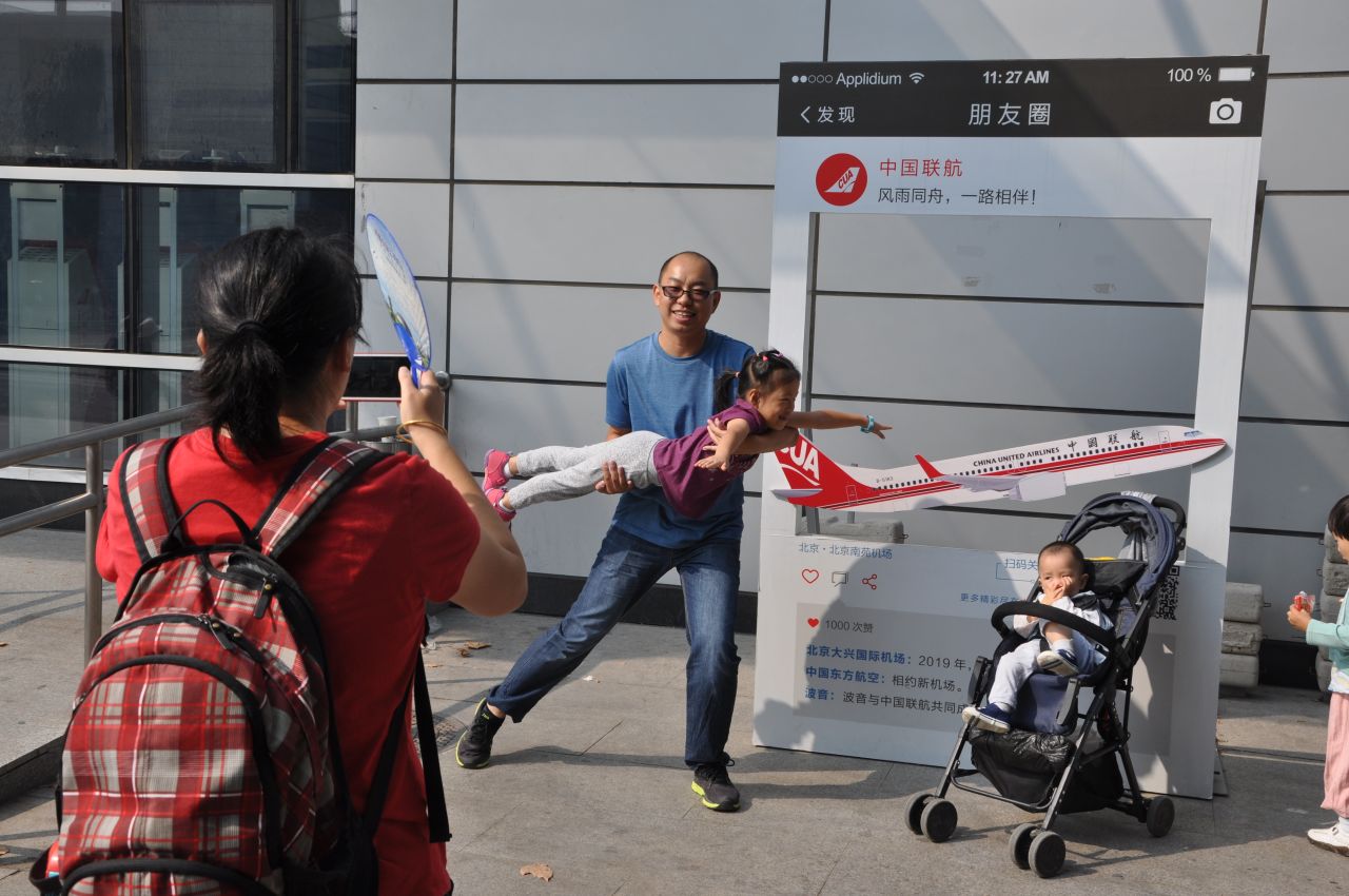 Wang Xiang and his young daughter pose in front of a sign commemorating the closure of Beijing's Nanyuan Airport on September 29.