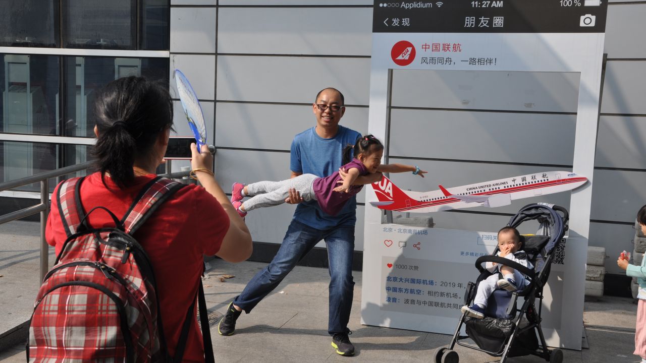 Wang Xiang and his young daughter pose in front of a sign commemorating the closure of Beijing's Nanyuan Airport on September 29.