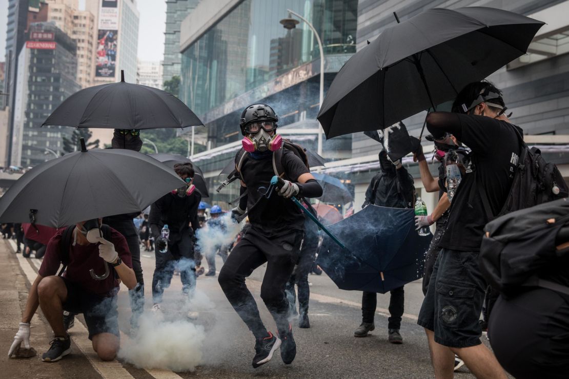 A pro-democracy protester throws a tear gas canister back at police amid clashes on Sunday.