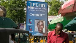Pedestrians walk past a billboard advertising the Tecno Mobile Camon 11 Pro smartphone device near Jagwal Electronics Market in Maiduguri, Nigeria, on Wednesday, May 1, 2019. Nigeria will propose a supplementary budget later this year to boost capital spending and fund a 67 percent increase in the minimum wage as government revenues improve, Budget Minister Udo Udoma said. Photographer: Jean Chung/Bloomberg via Getty Images