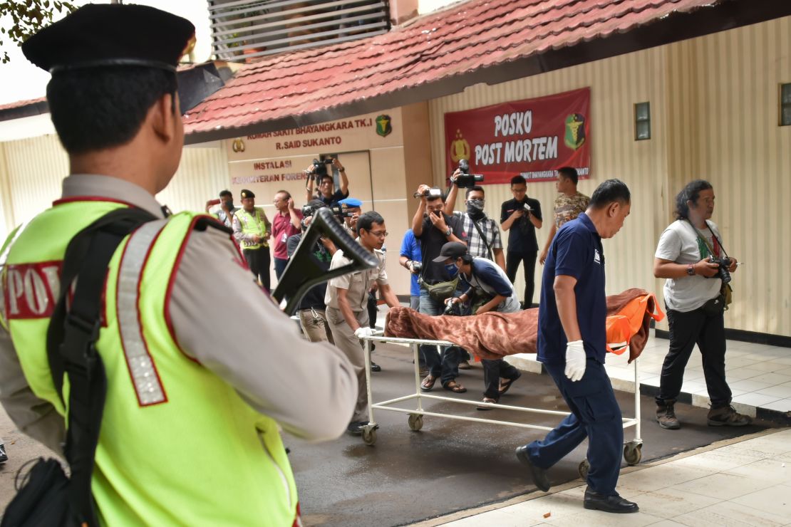 Indonesian police and forensic officials shift the body of a Canadian citizen who was killed during the January 14, 2016 terrorist attacks in Jakarta. The weapons used during the attack were funded by Adi Jihadi, who had taken a radicalized domestic worker from Hong Kong as his second wife.