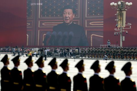 A screen shows Chinese President Xi Jinping delivering a speech at the start of the parade in Beijing.