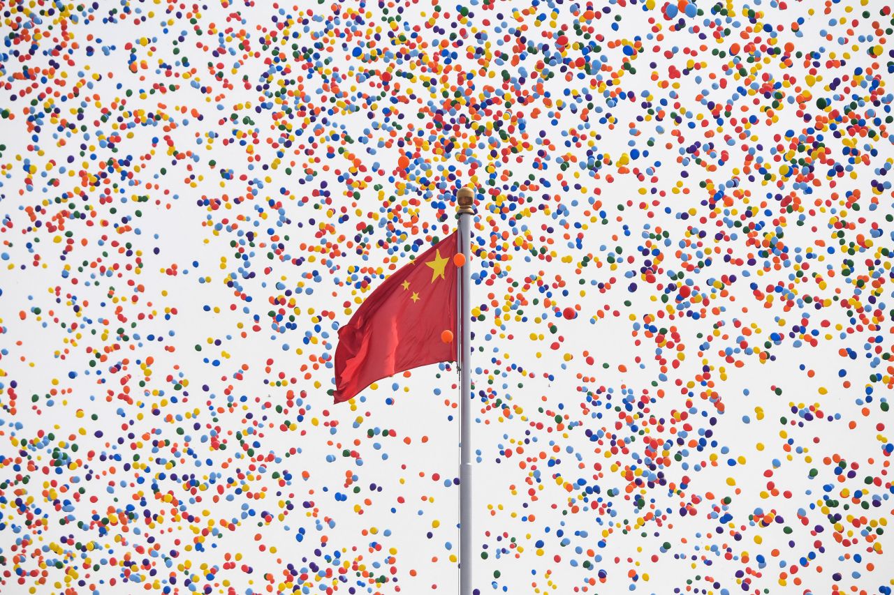 Balloons fly past a national flag at the end of a military parade at Tiananmen Square in Beijing.