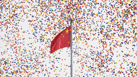 Balloons fly past a national flag at the end of a military parade at Tiananmen Square in Beijing.