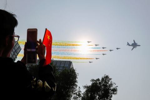 An onlooker photographs the Chinese military planes as they trail colored smoke during the celebrations.