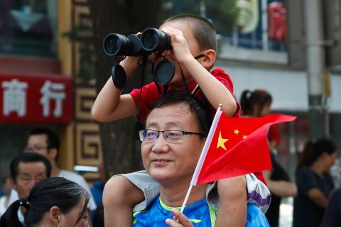 A child uses binoculars to watch the floats in the anniversary parade.