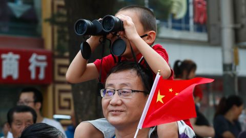 A child uses binoculars to watch the floats in the anniversary parade.