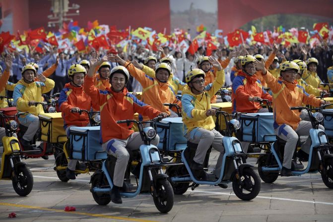 Participants dressed as deliverymen wave during the parade,