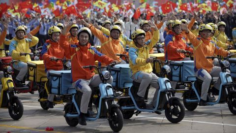 Participants dressed as deliverymen wave during the parade,